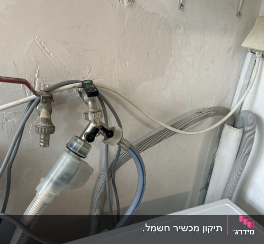 צינורות ומחברים על קיר ליד מכשיר חשמלי